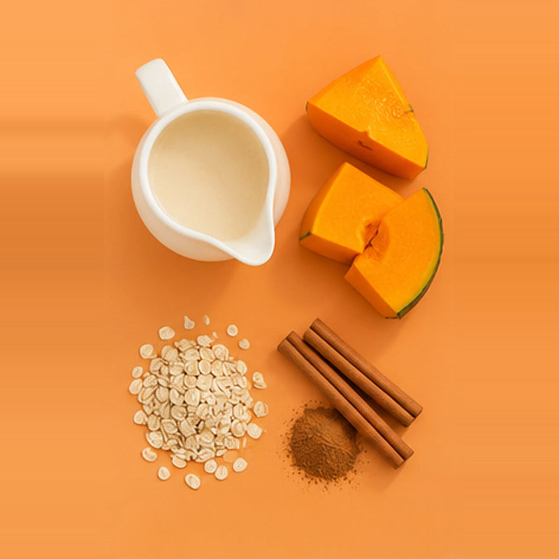 Pumpkin spice smoothie ingredients photographed from above: pumpkin, milk and cinnamon on an orange backdrop